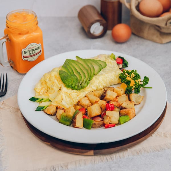 Mikayla's Cafe breakfast omelet with avocado, home fries, and a glass of orange juice.