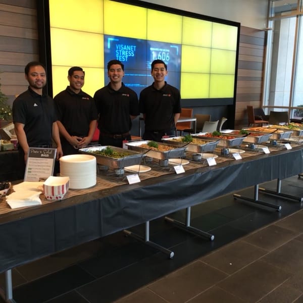 Four Mikayla's Cafe staff stand behind a buffet table laden with breakfast dishes and plates.