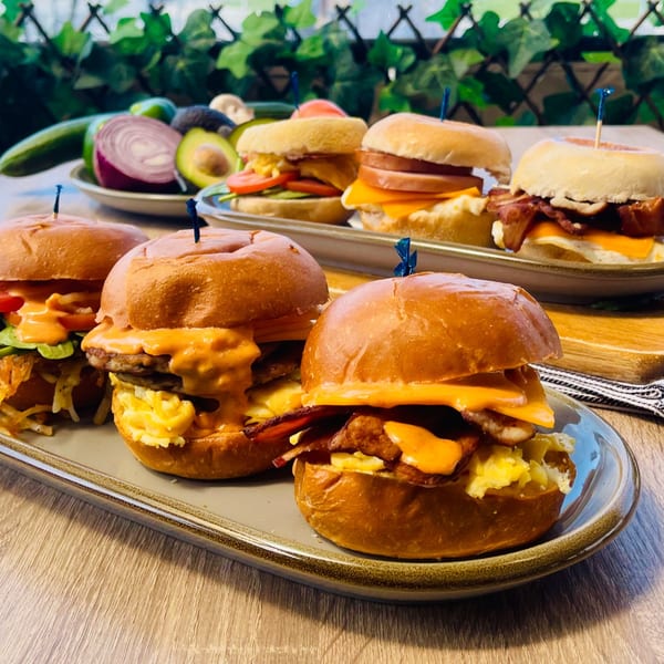 A close-up of Mikayla's Cafe breakfast sliders with eggs, bacon, cheese, and sauce on a wooden table.