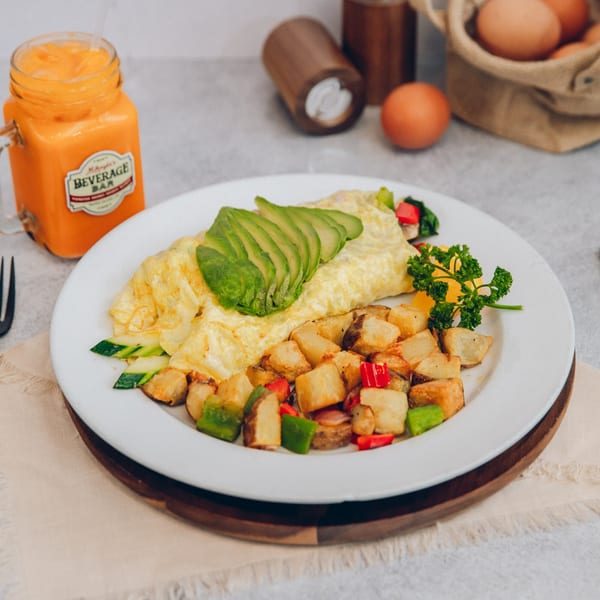 Mikayla's Cafe breakfast omelet with avocado, home fries, and a glass of orange juice.