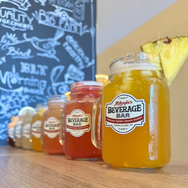 Row of Mikayla's Cafe beverages in mason jars, with a pineapple slice on the front drink.