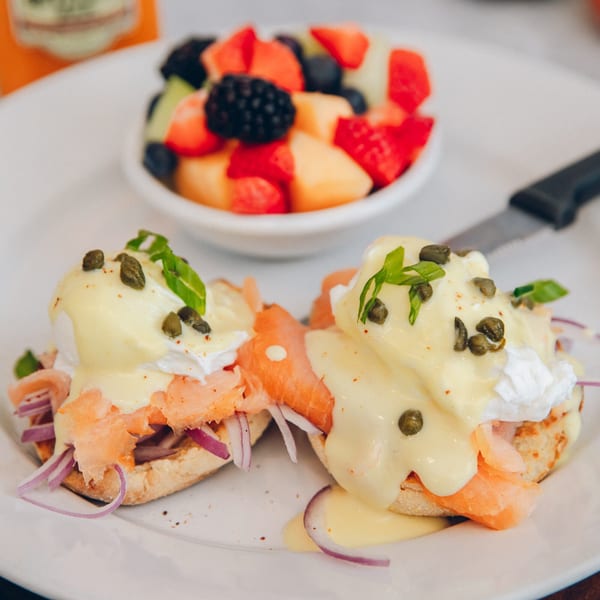 Smoked salmon eggs Benedict with capers and red onion, served with a side of fresh fruit.